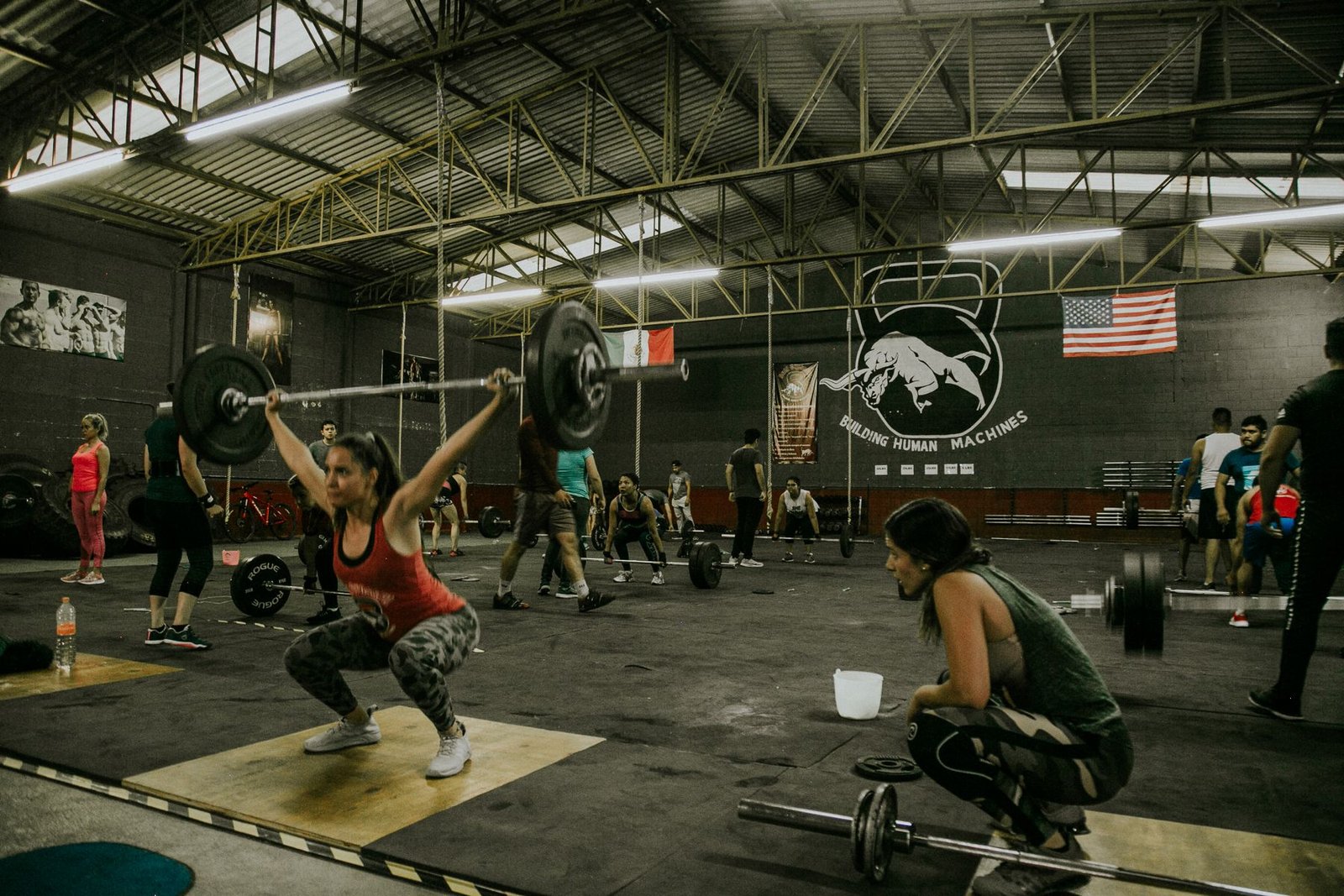 CrossFit class training with barbells on the gym floor, with athletes spread across the box